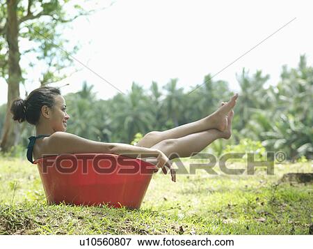 Young woman sitting in bowl outdoors, side view, smiling View Large Photo Image Stock Photo - Young woman sitting in bowl outdoors, side view, smiling. Fotosearch