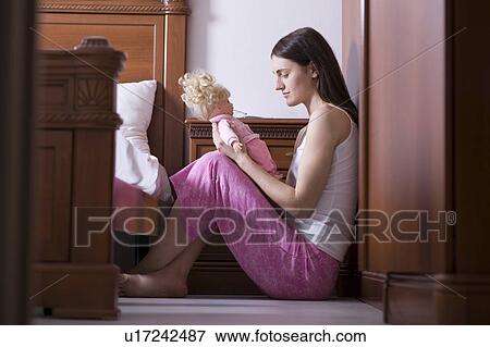 Young woman sitting on the floor and holding doll View Large Photo Image Stock Photo - Young woman sitting on the floor and holding doll. Fotosearch