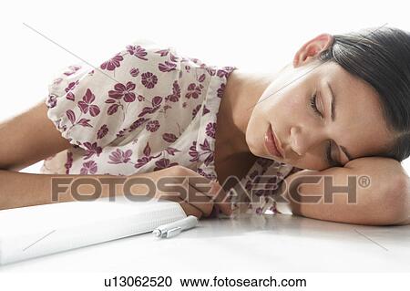 Stock Image - Young woman sleeping on table, close-up. Fotosearch