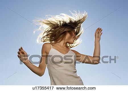 Young woman standing in front of sun tossing hair, low angle view View Large Photo Image Stock Photo - Young woman standing in front of sun tossing hair, low angle view. Fotosearch