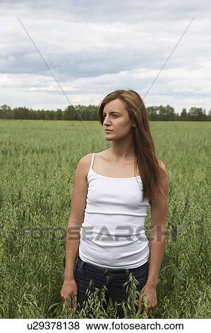 Stock Photo - Young woman standing on field. Fotosearch