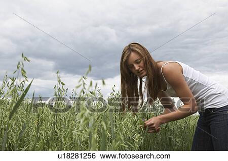 Young woman standing on field View Large Photo Image Stock Photograph - Young woman standing on field. Fotosearch