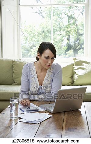 Stock Photo - Young woman using calculator and laptop. Fotosearch