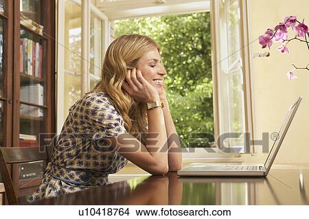 Young woman using laptop in living room View Large Photo Image Picture - Young woman using laptop in living room. Fotosearch