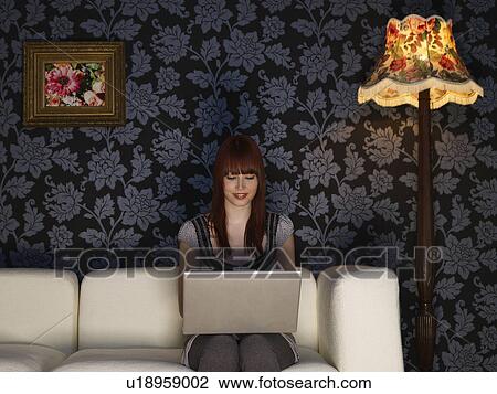 Young woman using laptop sitting on sofa View Large Photo Image Stock Image - Young woman using laptop sitting on sofa. Fotosearch