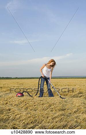 Stock Image - Young Woman Vacuuming a Field. Fotosearch