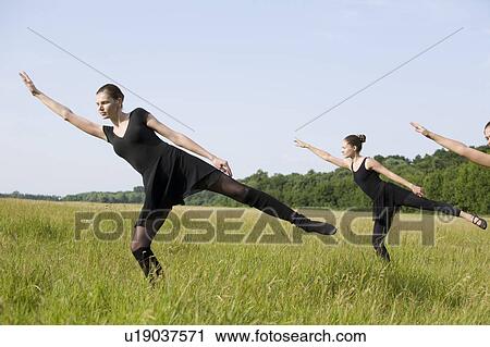 Stock Image - Young women stretch in a field. Fotosearch