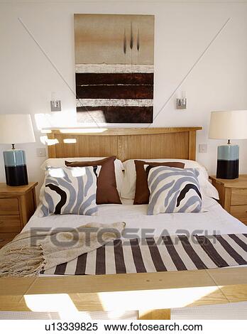 Stock Photography - Abstract picture above bed with patterned cushions striped throw in modern bedroom. Fotosearch