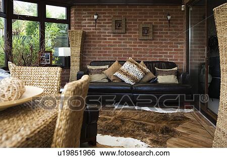 Animalprint cushions on black leather sofa in dining room extension with animalskin rug on the floor View Large Photo Image Stock Photograph - Animalprint cushions on black leather sofa in dining room extension with animalskin rug on the floor. Fotosearch