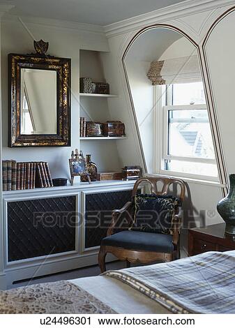 Stock Image - Antique chair in front of dormer window in country bedroom. Fotosearch