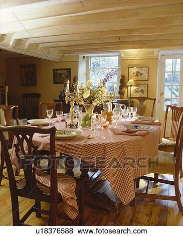 antique chairs and pink checked cloth with place settings on table in country dining room with stripped ceiling beams View Large Photo Image Stock Photo - antique chairs and pink checked cloth with place settings on table in country dining room with stripped ceiling beams. Fotosearch