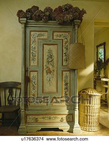 Antique cupboard with painted floral decoration beside tall lidded basket in country hall View Large Photo Image Picture - Antique cupboard with painted floral decoration beside tall lidded basket in country hall. Fotosearch
