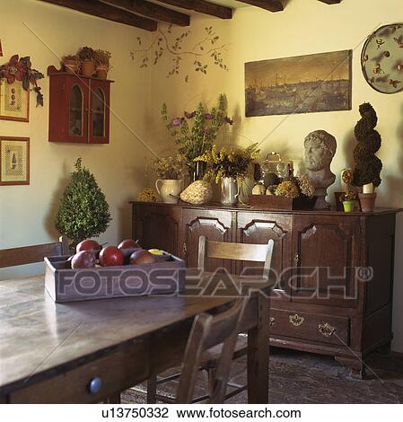 Stock Image - Antique sideboard and table in country dining room. Fotosearch