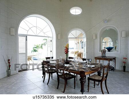 Antique table and chairs in white Caribbean dining room with white tiled floor View Large Photo Image Stock Photography - Antique table and chairs in white Caribbean dining room with white tiled floor. Fotosearch