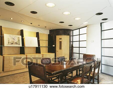 Stock Image - Antique table and studded leather chairs in modern boardroom in city office. Fotosearch
