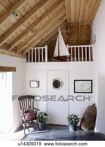 Stock Photo - Antique Windsor chair in white hall with wooden ceiling and model sailing-boat on gallery. Fotosearch