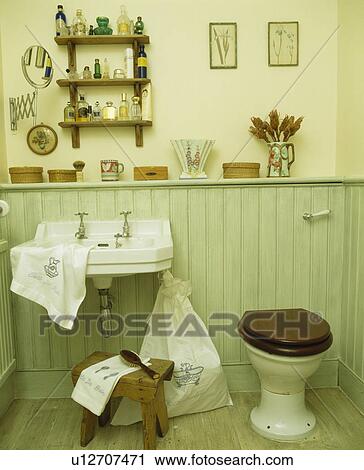 Stock Image - Basin and toilet in pastel green tongue+groove panelled bathroom. Fotosearch