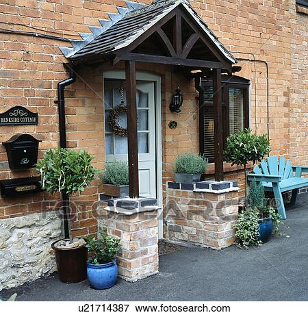 Stock Photo - Bay trees in pots on either side of porch on brick country cottage. Fotosearch