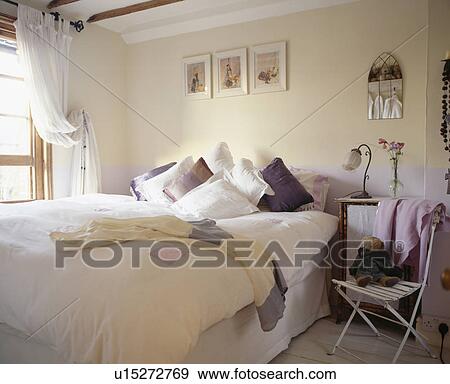Stock Photo - Bed piled with pillows in cream country bedroom. Fotosearch