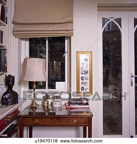 Beige blind on window above table with cream lamp beside patio door in small living room View Large Photo Image Stock Photo - Beige blind on window above table with cream lamp beside patio door in small living room. Fotosearch