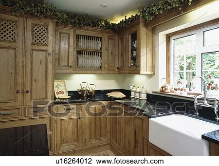 Stock Image - Belfast sink in country kitchen with fitted oak units. Fotosearch