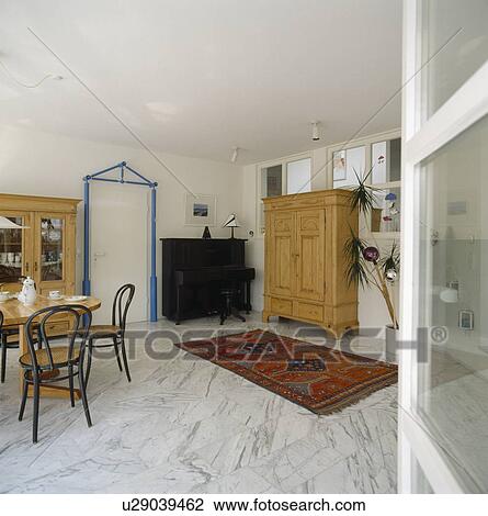 Bentwood chairs and red oriental rug on marble flooring in modern white dining room with large pine cupboard View Large Photo Image Stock Image - Bentwood chairs and red oriental rug on marble flooring in modern white dining room with large pine cupboard. Fotosearch