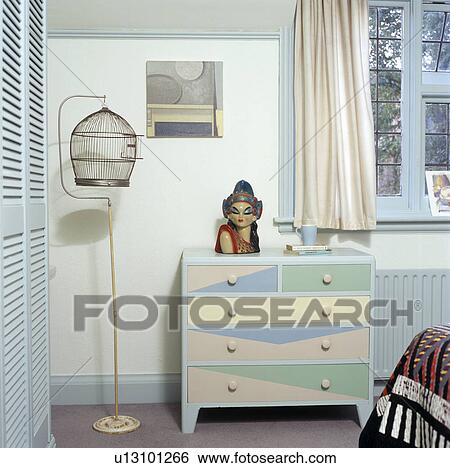 Birdcage and turquoise+white painted chest of drawers in small bedroom View Large Photo Image Stock Photograph - Birdcage and turquoise+white painted chest of drawers in small bedroom. Fotosearch