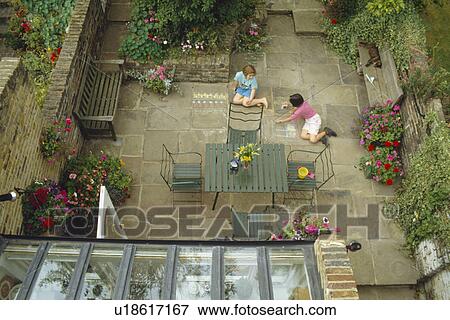 Birdseye view of children playing in paved town garden with table and chairs on patio View Large Photo Image Stock Photo - Birdseye view of children playing in paved town garden with table and chairs on patio. Fotosearch