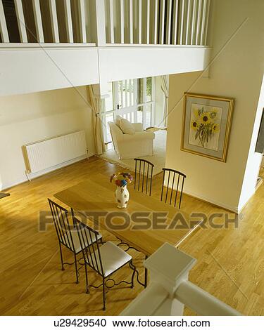 Stock Image - Birdseye view of pale wood dining table in barn conversion with wooden flooring. Fotosearch