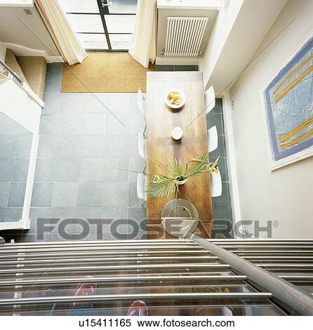 Stock Photography - Birdseye view of wood table in modern dining room with grey flooring. Fotosearch