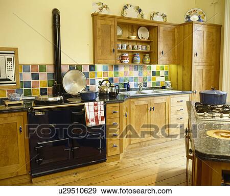 Stock Photo - Black Aga oven in traditional yellow kitchen with wooden fitted units. Fotosearch