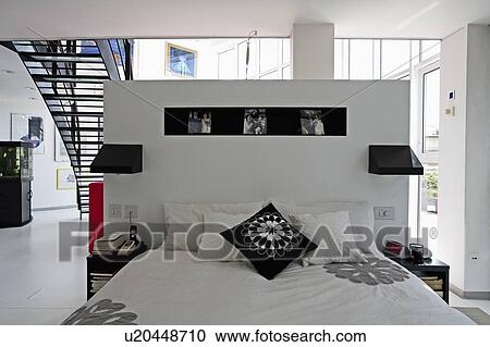 Black and whtie cushions and bedlinen on bed in modern white open-plan loft conversion bedroom View Large Photo Image Stock Image - Black and whtie cushions and bedlinen on bed in modern white open-plan loft conversion bedroom . Fotosearch