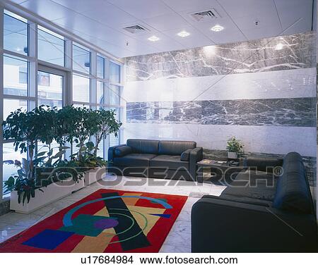 Black leather sofas and green plants in office reception area with marble walls and brightly coloured rug View Large Photo Image Picture - Black leather sofas and green plants in office reception area with marble walls and brightly coloured rug. Fotosearch