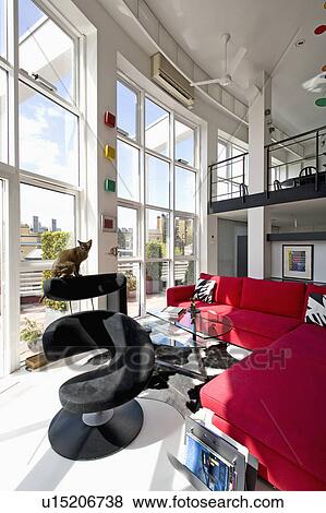 Black leather spiral-shaped chair and large red sofas in modern open-plan loft conversion living room View Large Photo Image Stock Photo - Black leather spiral-shaped chair and large red sofas in modern open-plan loft conversion living room. Fotosearch