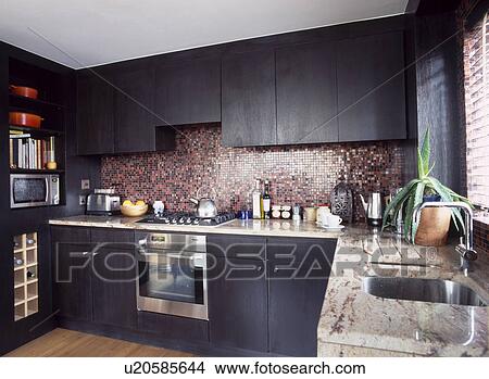 Black stained oak units in modern kitchen with mosaic tiled splashback and stainless steel oven View Large Photo Image Picture - Black stained oak units in modern kitchen with mosaic tiled splashback and stainless steel oven. Fotosearch