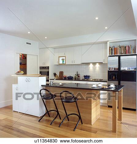 Black stools at black granite-topped breakfast bar in modern white kitchen with wooden flooring View Large Photo Image Stock Image - Black stools at black granite-topped breakfast bar in modern white kitchen with wooden flooring. Fotosearch