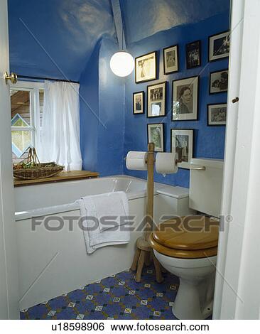 Stock Photograph - Black+white photographs in small blue attic bathroom. Fotosearch