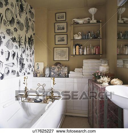 Black+white seashell wallpaper above bath in small cream bathroom View Large Photo Image Stock Photo - Black+white seashell wallpaper above bath in small cream bathroom. Fotosearch