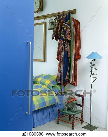 Bloue door open to clothes on rack and bed with blue checked linen in modern bedroom View Large Photo Image Stock Photo - Bloue door open to clothes on rack and bed with blue checked linen in modern bedroom. Fotosearch