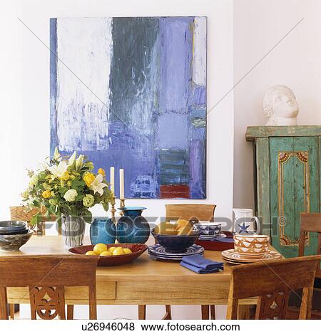 Stock Photo - Blue abstract picture in dining room with blue vases and napkins on wooden table. Fotosearch