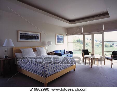 Blue checked bedlinen on bed in modern bedroom with patio doors and view of the garden View Large Photo Image Stock Image - Blue checked bedlinen on bed in modern bedroom with patio doors and view of the garden. Fotosearch