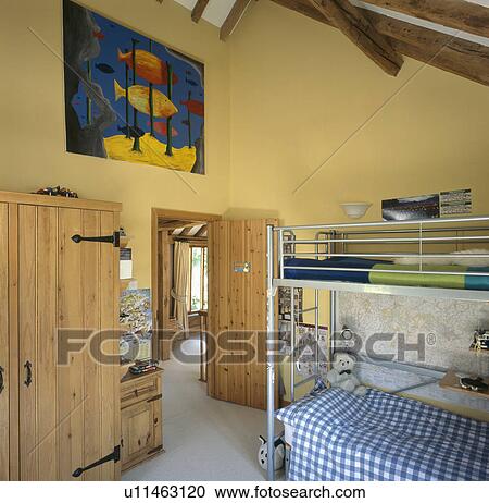 Blue checked bedlinen on metal bunk bed in child's yellow bedroom with large picture above pine wardrobe View Large Photo Image Stock Image - Blue checked bedlinen on metal bunk bed in child's yellow bedroom with large picture above pine wardrobe. Fotosearch