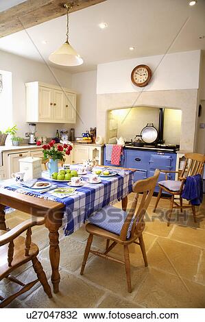 Blue checked cloth on wooden table with wooden chairs in country kitchen with stone flooring and blue Aga oven View Large Photo Image Stock Image - Blue checked cloth on wooden table with wooden chairs in country kitchen with stone flooring and blue Aga oven. Fotosearch