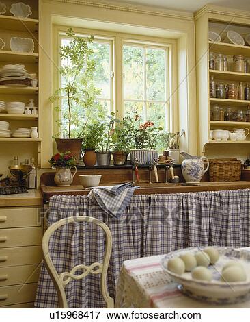 Blue checked curtains on cupboards below window in cottage kitchen View Large Photo Image Stock Photo - Blue checked curtains on cupboards below window in cottage kitchen. Fotosearch