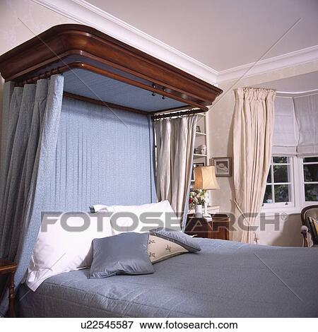 Stock Photo - Blue drapes and quilted bedcover on half-tester bed in townhouse bedroom. Fotosearch