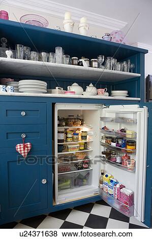 Stock Photo - Blue kitchen dresser with marble shelves and fitted fridge with open door. Fotosearch