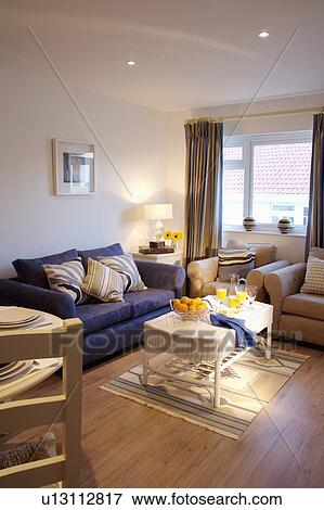 Blue sofa and white wicker table in modern white living room with wooden flooring View Large Photo Image Stock Photo - Blue sofa and white wicker table in modern white living room with wooden flooring. Fotosearch