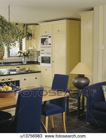 Blue upholstered chairs and pale wood table in cream kitchen dining room View Large Photo Image Stock Image - Blue upholstered chairs and pale wood table in cream kitchen dining room. Fotosearch