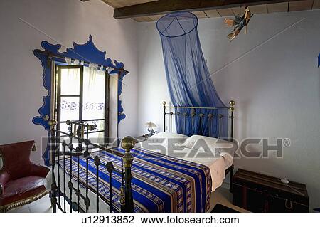 Blue voile mosquito net above antique brass bed with patterned blue throw in Mallorcan bedroom View Large Photo Image Stock Image - Blue voile mosquito net above antique brass bed with patterned blue throw in Mallorcan bedroom. Fotosearch