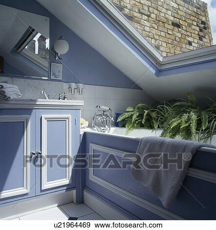 Blue+white panelled bath and vanity unit in small blue attic bathroom View Large Photo Image Stock Photo - Blue+white panelled bath and vanity unit in small blue attic bathroom. Fotosearch